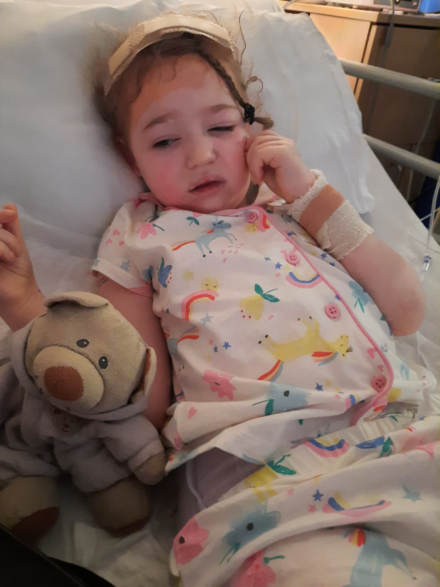 Olivia recovering with her teddy after brain surgery