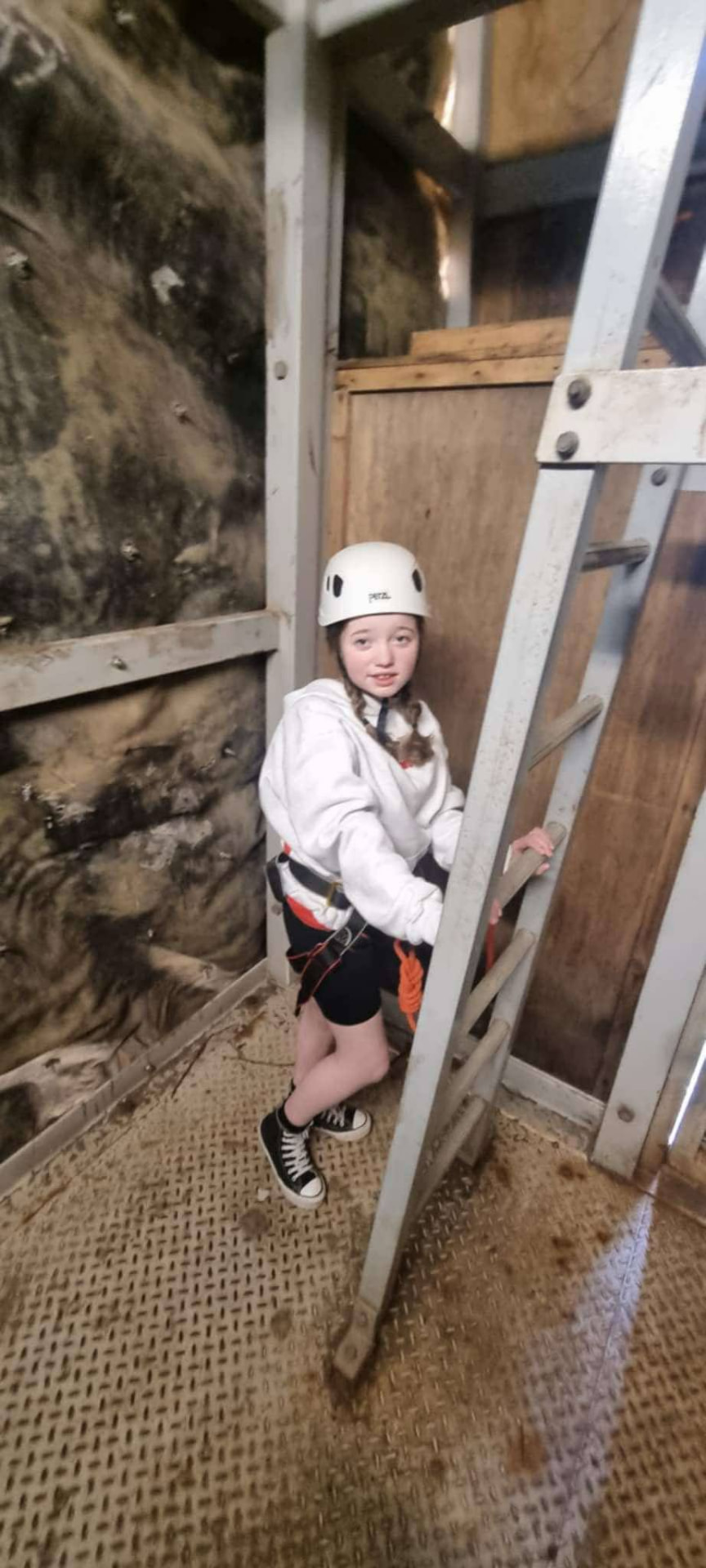 Olivia climbing a wall in a harness and helmet